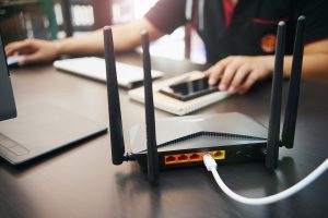 A person on a computer next to a router.