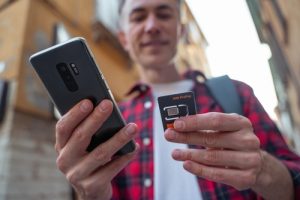 Man in red plaid shirt with mobile phone and sim card