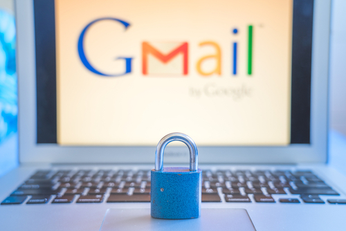 blue closed metal lock on laptop touchpad with Gmail logo on the laptop screen in the background