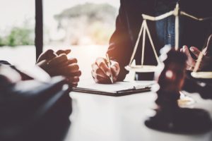 Business woman and lawyers discussing contract papers with brass scale on wooden desk in office