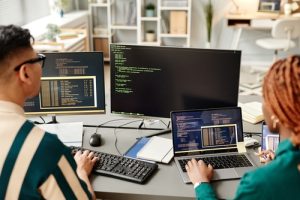 High angle of two IT developers using computers while reviewing code in office software code audit