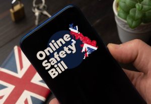 Online Safety Bill (OSB) UK concept: man hold a smartphone over a wooden desktop